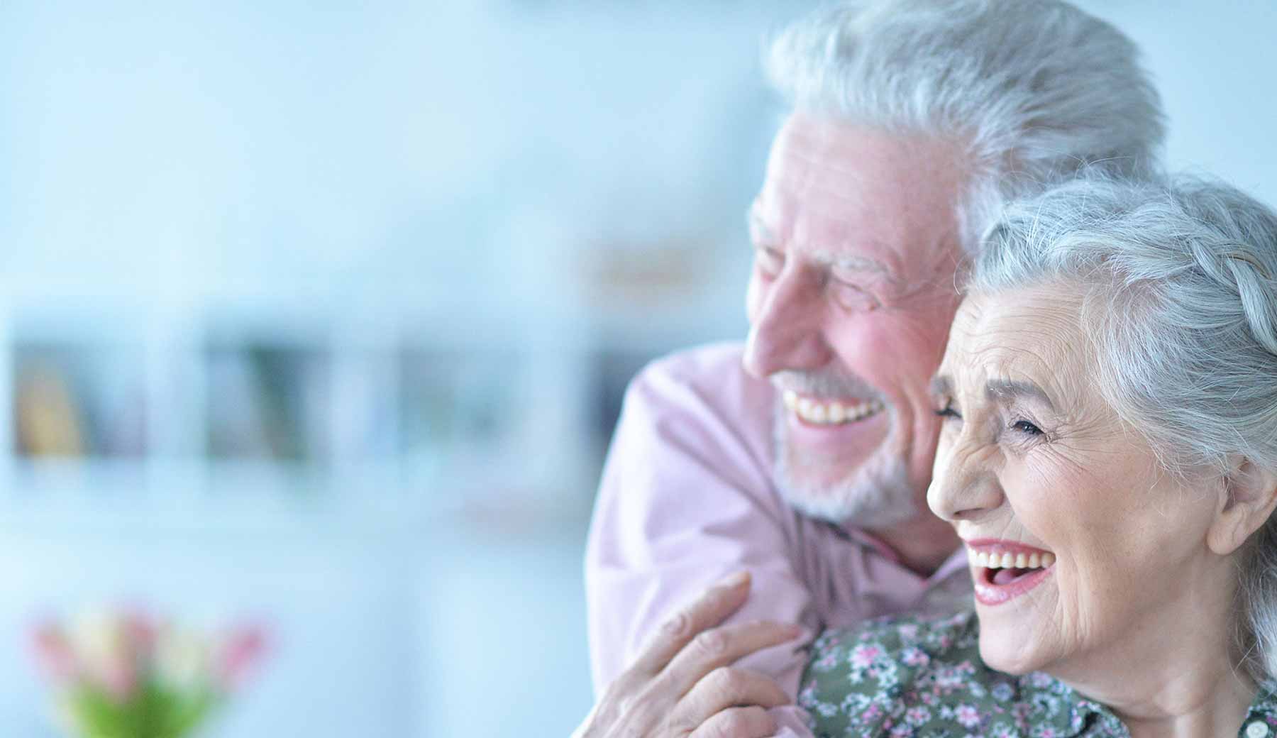 an elderly couple smiling with their new dental implants