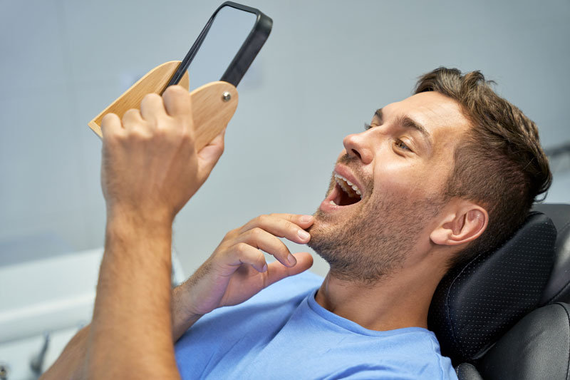 guy looking into mirror at teeth