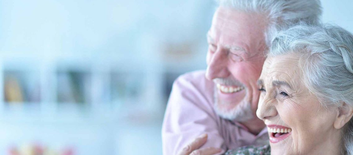 an elderly couple smiling with their new dental implants