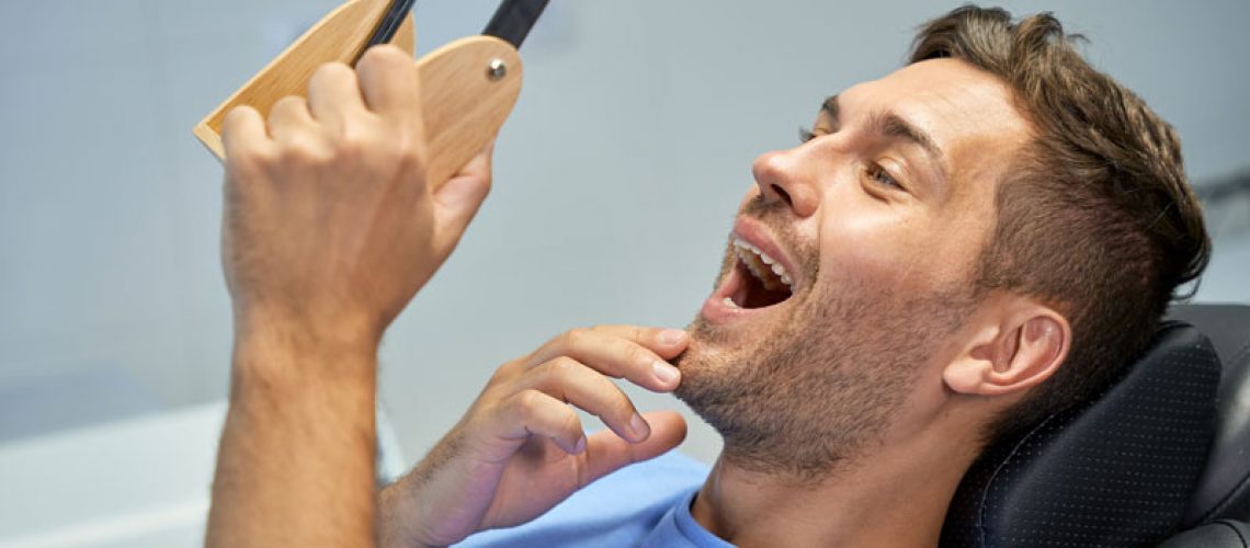 guy looking into mirror at teeth